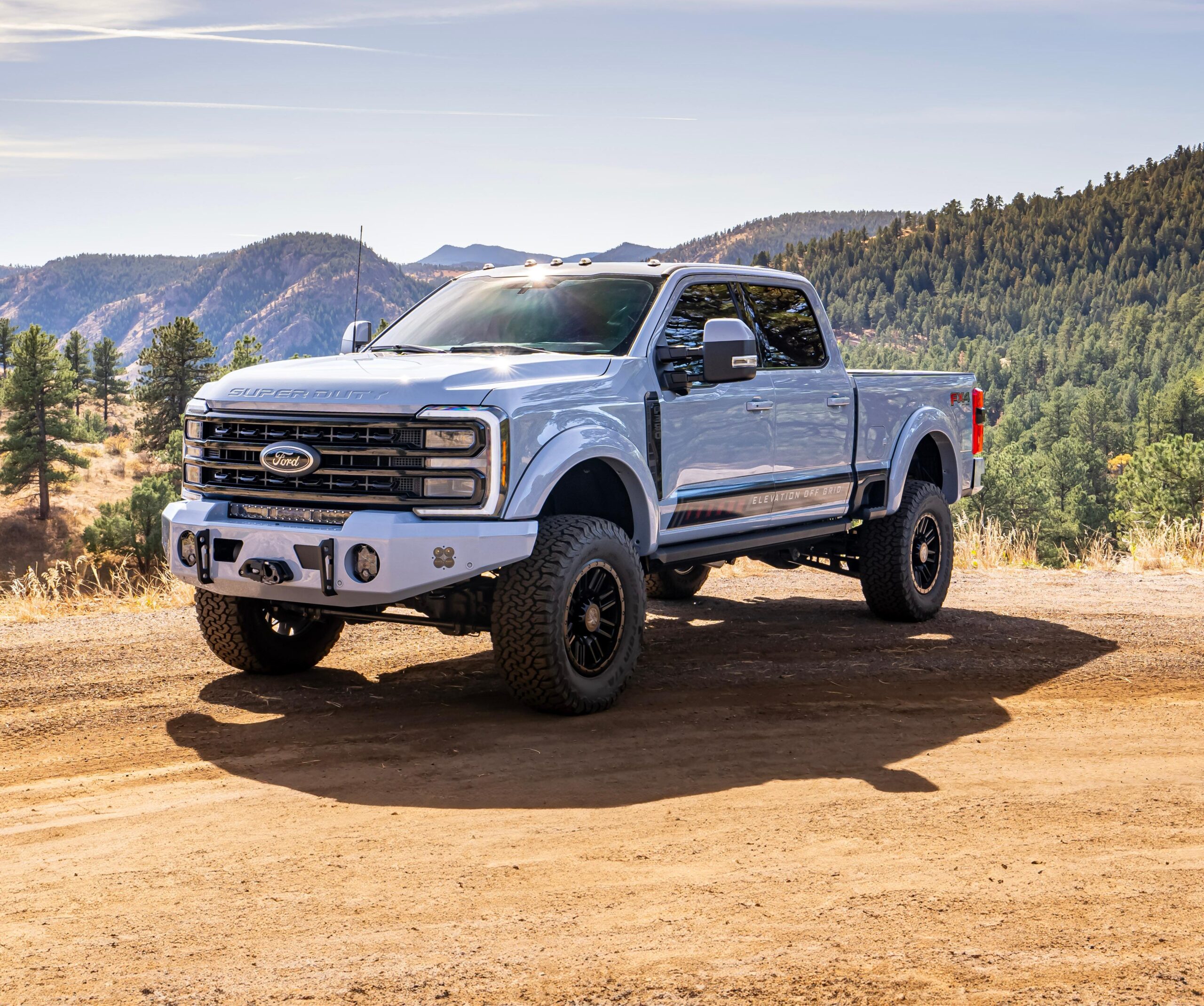 350 Glacier parked in dirt with mountain views behind and blue sky