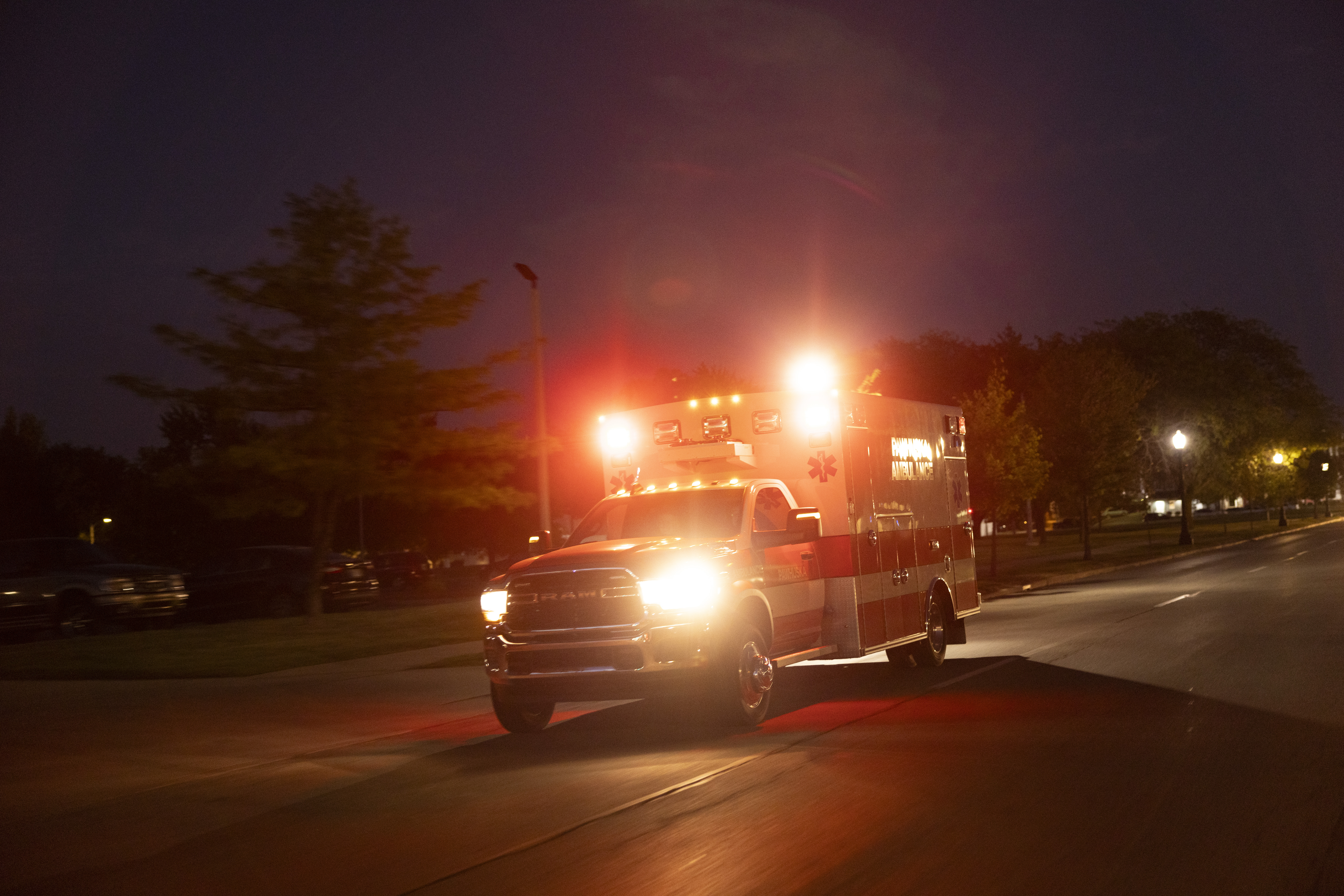ambulance with LiquidSpring suspension with red flashing lights speeding down a road at night