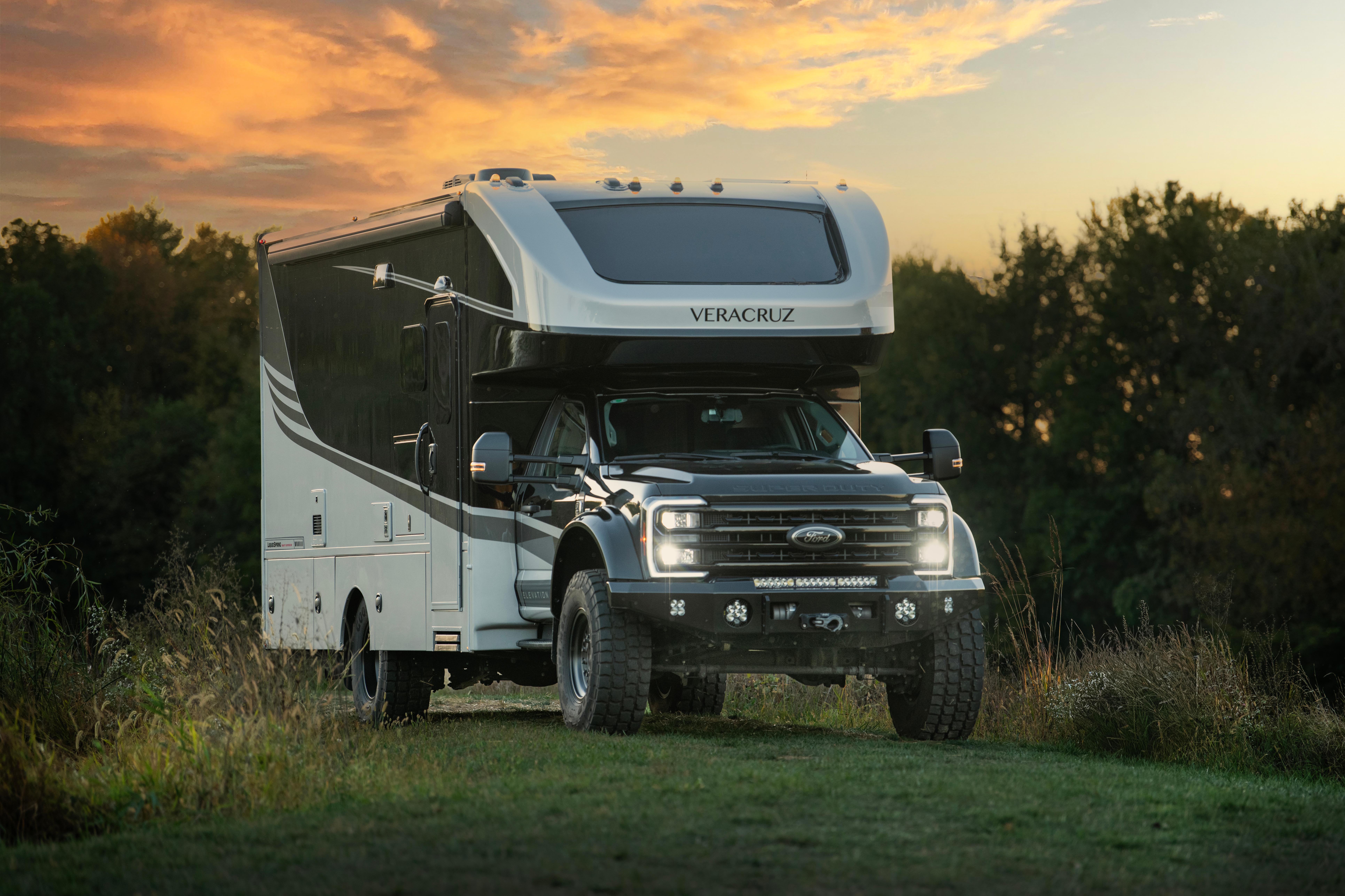 Super C Verzcruz RV on green grass with a sunset behind it